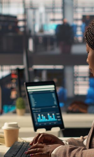 Professional business staff managing financial data to solve tasks for development, report writing at desk. Focused female manager using expertise to accomplish administrative tasks. Camera A.